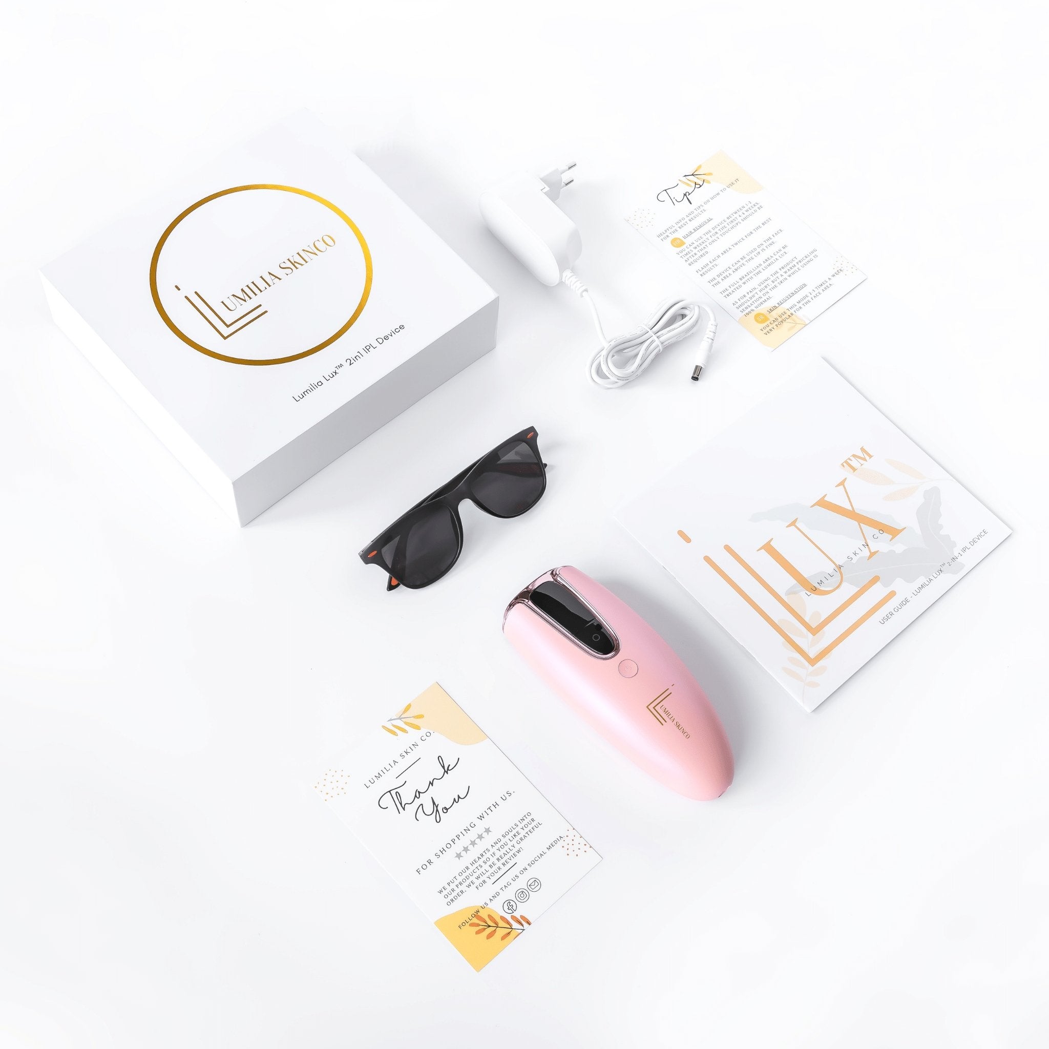 Pink Lumilia Lux 2in1 IPL Laser Hair Removal and Skin Rejuvenation Device – full kit shown flat lay with branded box, charger, manual, sunglasses, and thank-you card.