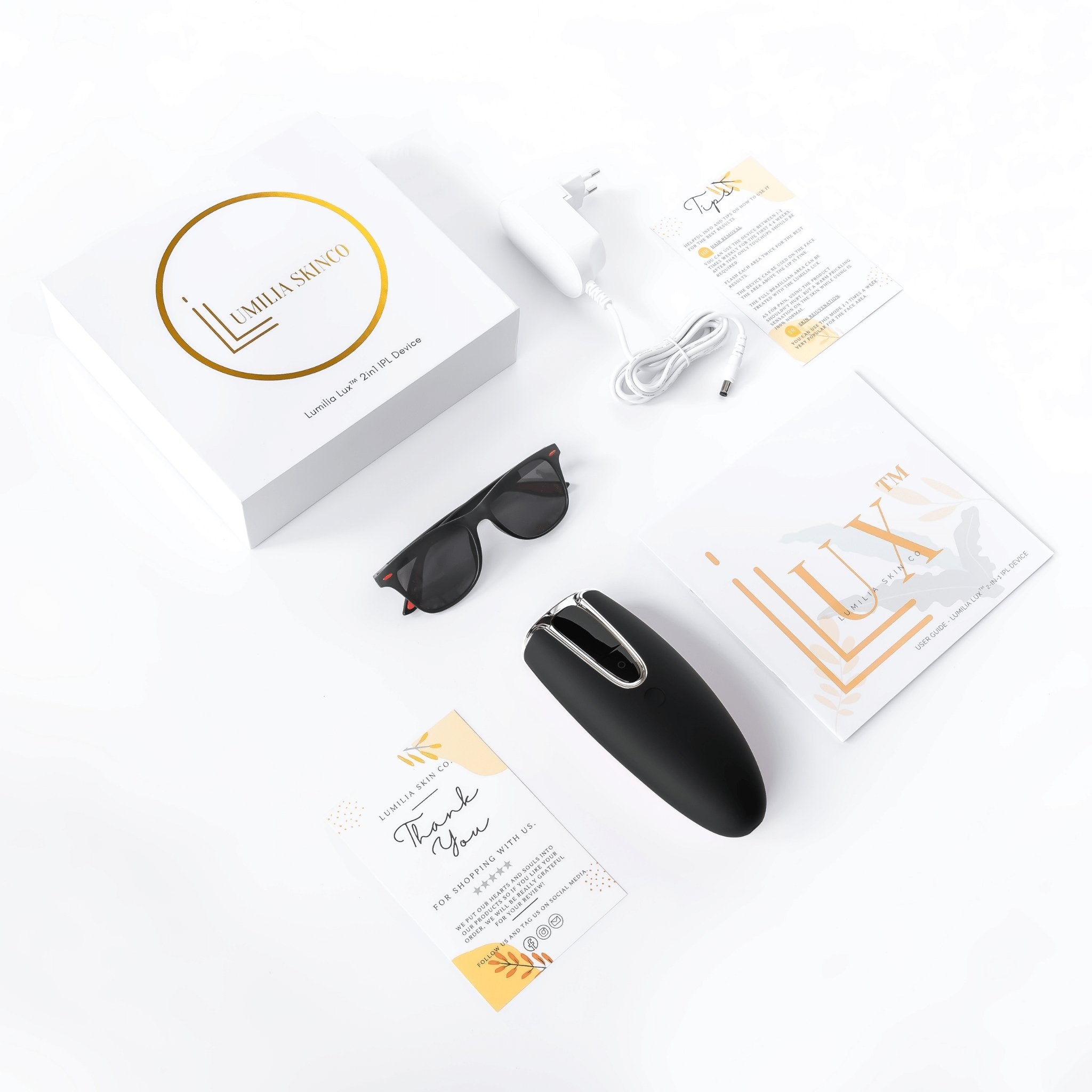 Black Lumilia Lux 2in1 IPL laser handset with silver trim and full packaging – includes charger, guides, sunglasses, and official Lumilia Skin Co. box