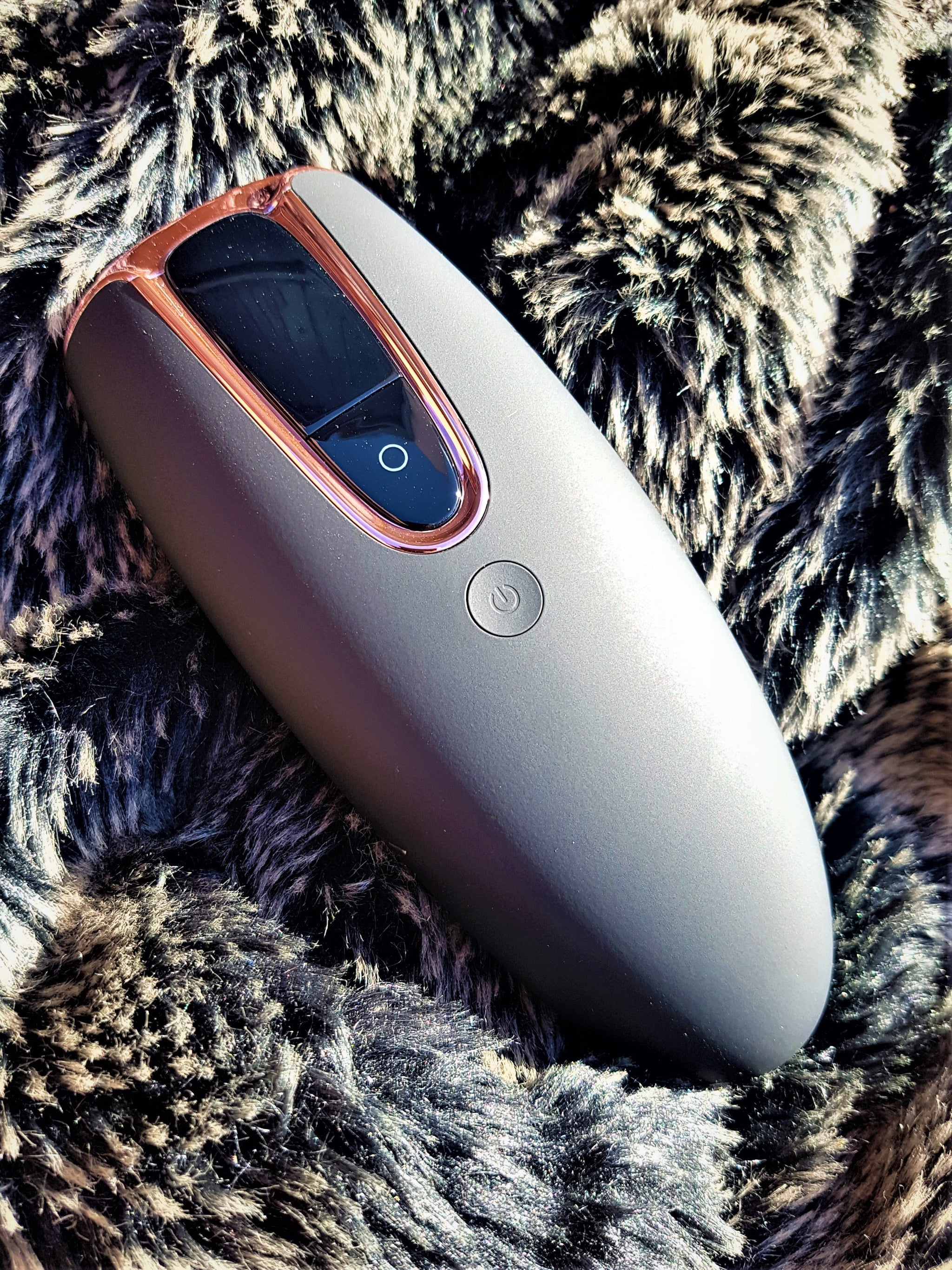 Lumilia Lux™ 2in1 IPL Laser Hair Removal & Skin Rejuvenation Device in matte black with rose trim, displayed on soft faux fur – luxury and comfort.