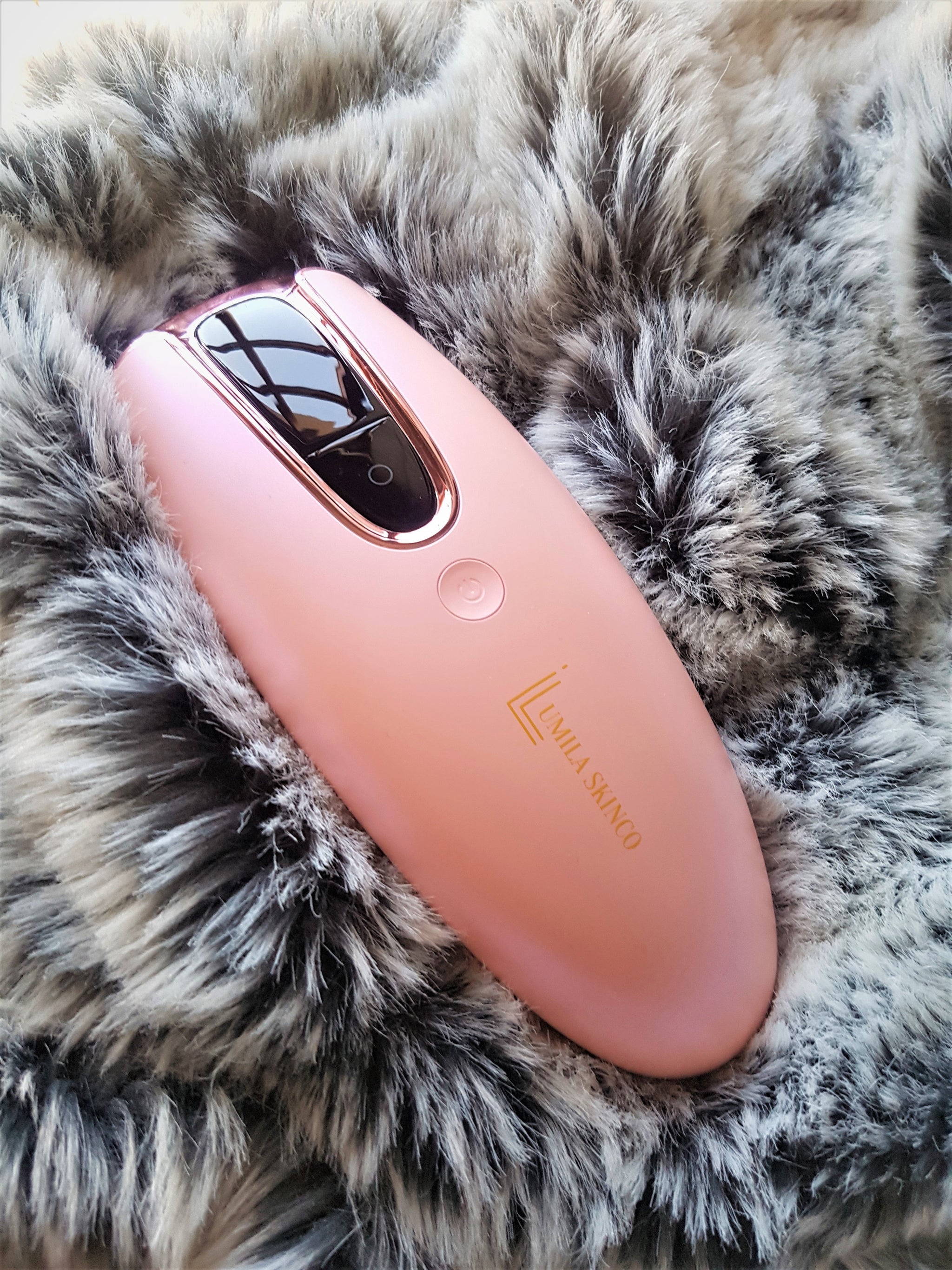 Lumilia Lux™ 2in1 IPL Laser Hair Removal & Skin Rejuvenation Device in Pink with rose trim, displayed on soft faux fur – luxury and comfort.