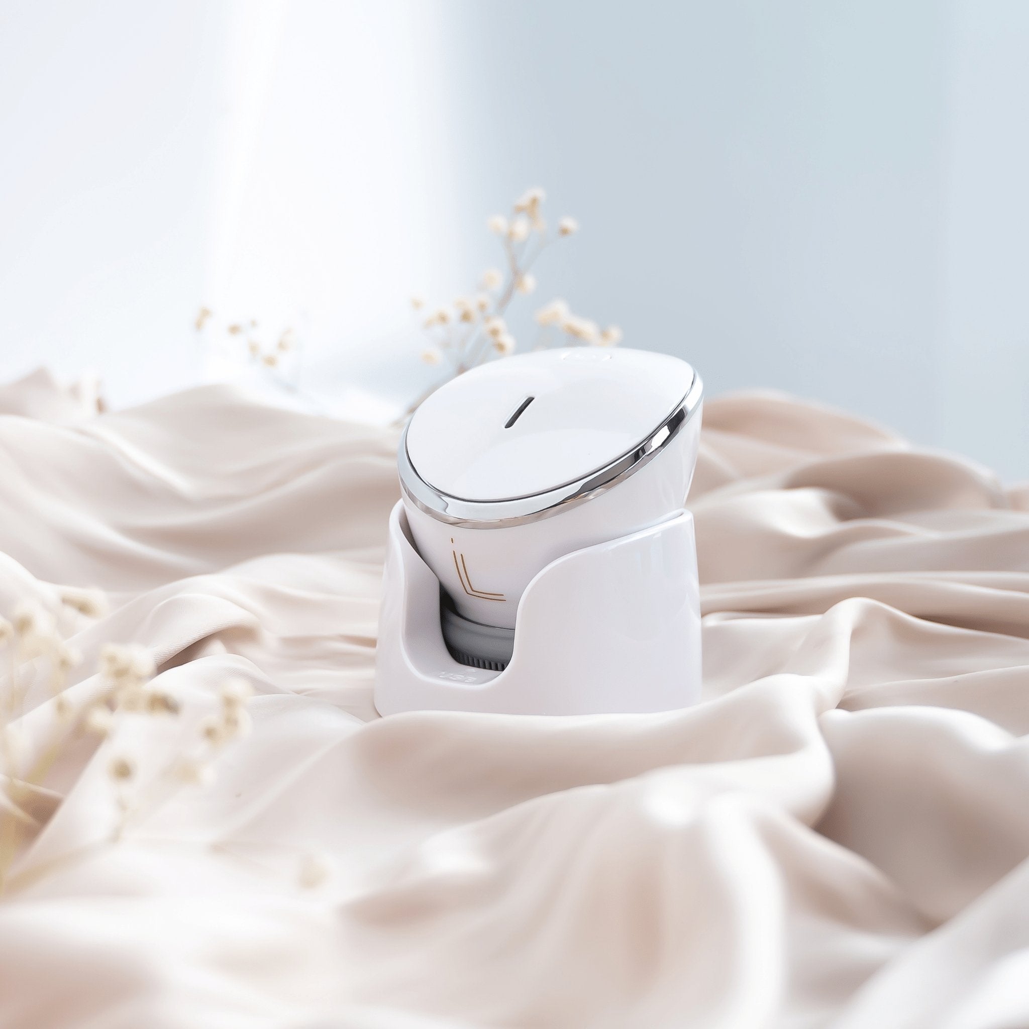 Lumilia NEO 3in1 Facial Cleansing & Massage Device in white, elegantly displayed on soft satin with floral details – luxury at-home skincare device for deep cleansing and rejuvenation.