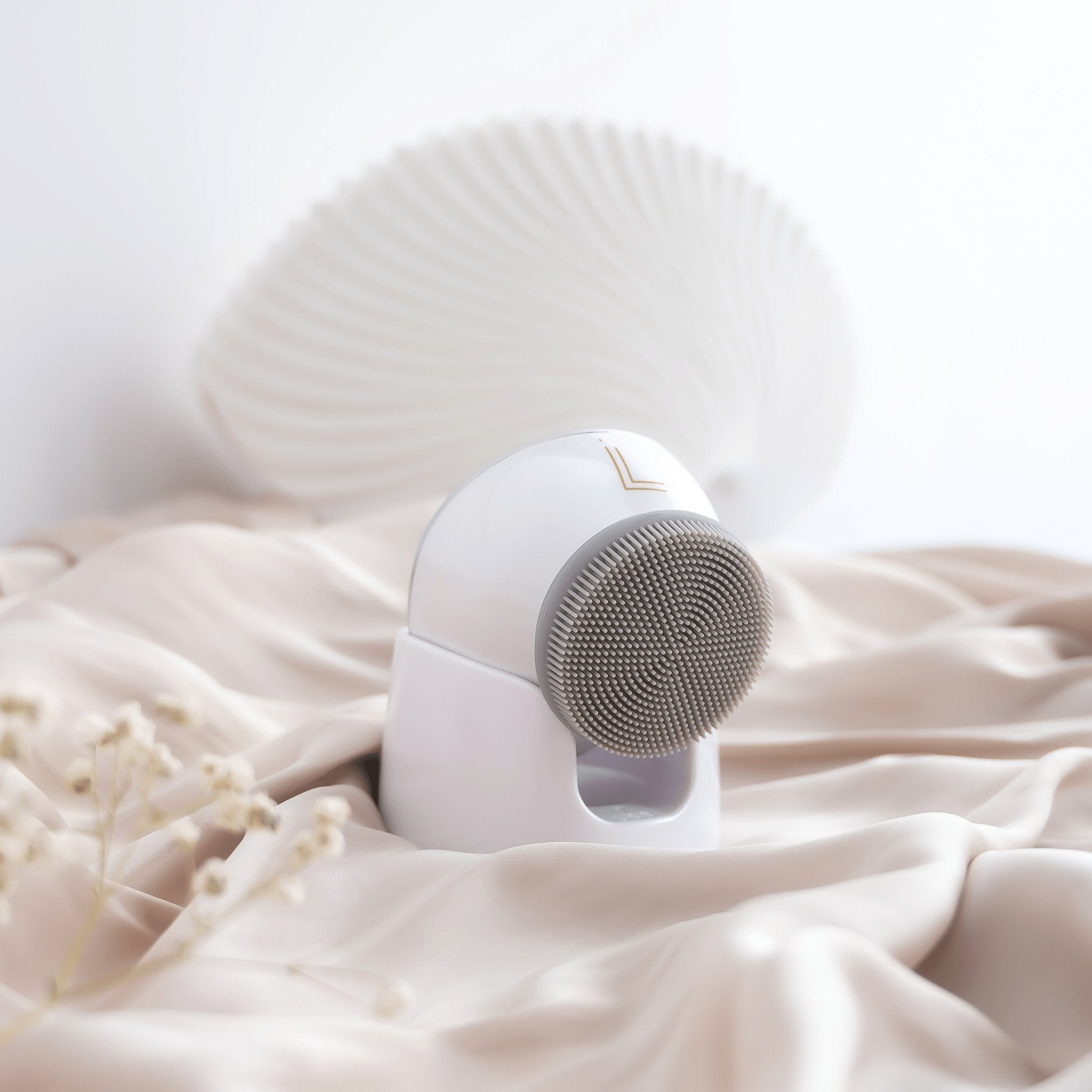 Lumilia NEO 3in1 Facial Cleansing & Massage Device in white, elegantly displayed on soft satin with floral details – premium at-home skincare tool for deep cleansing and rejuvenation.